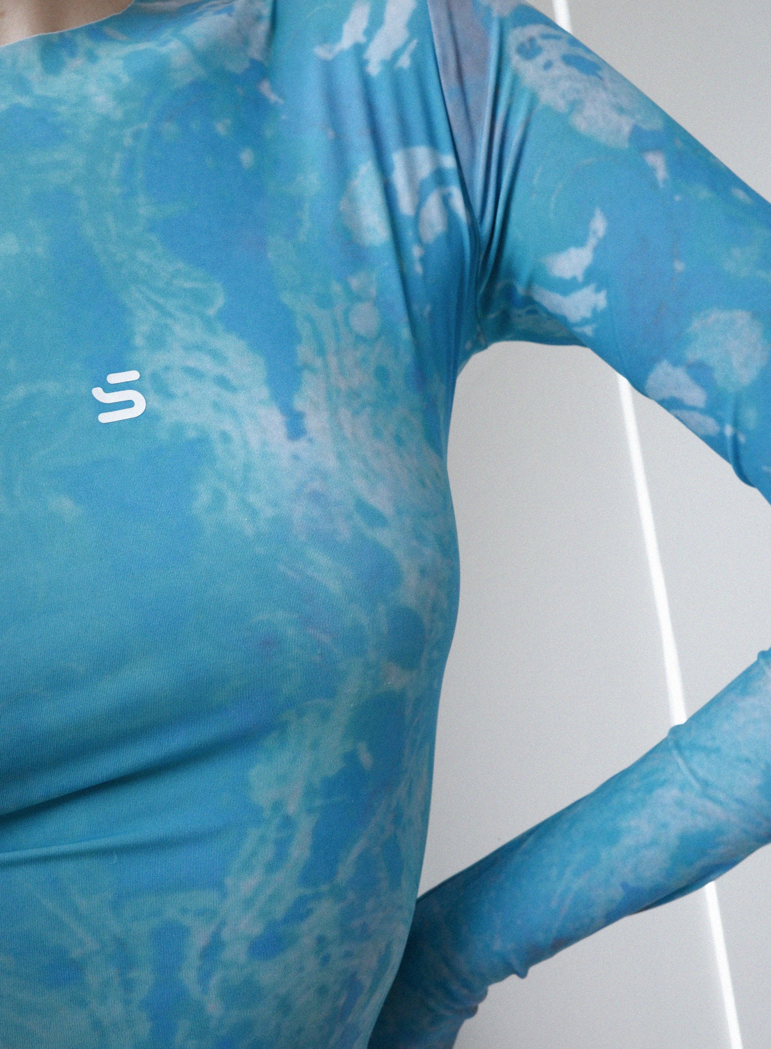 Person wearing a blue patterned second-skin longsleeve in an indoor setting
