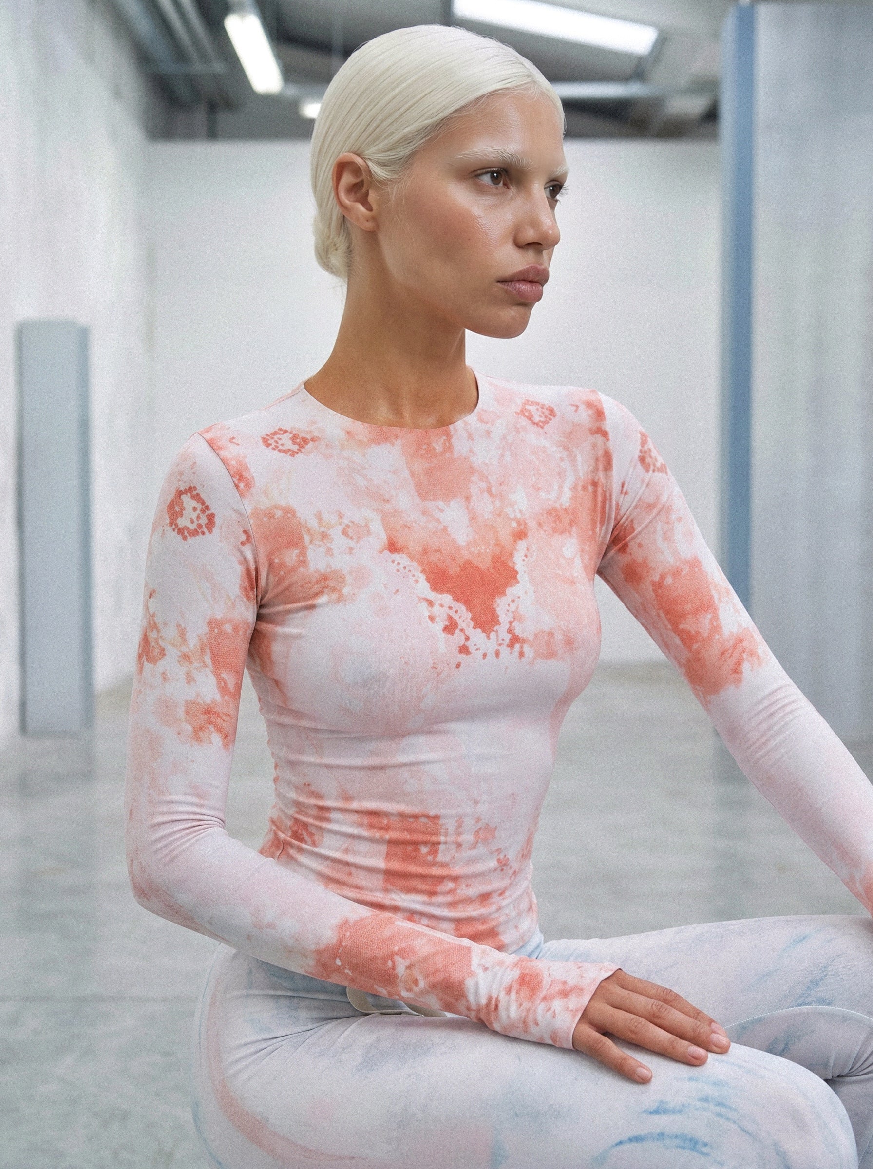 Person wearing a long-sleeve top with a tie-dye pattern in a futuristic setting