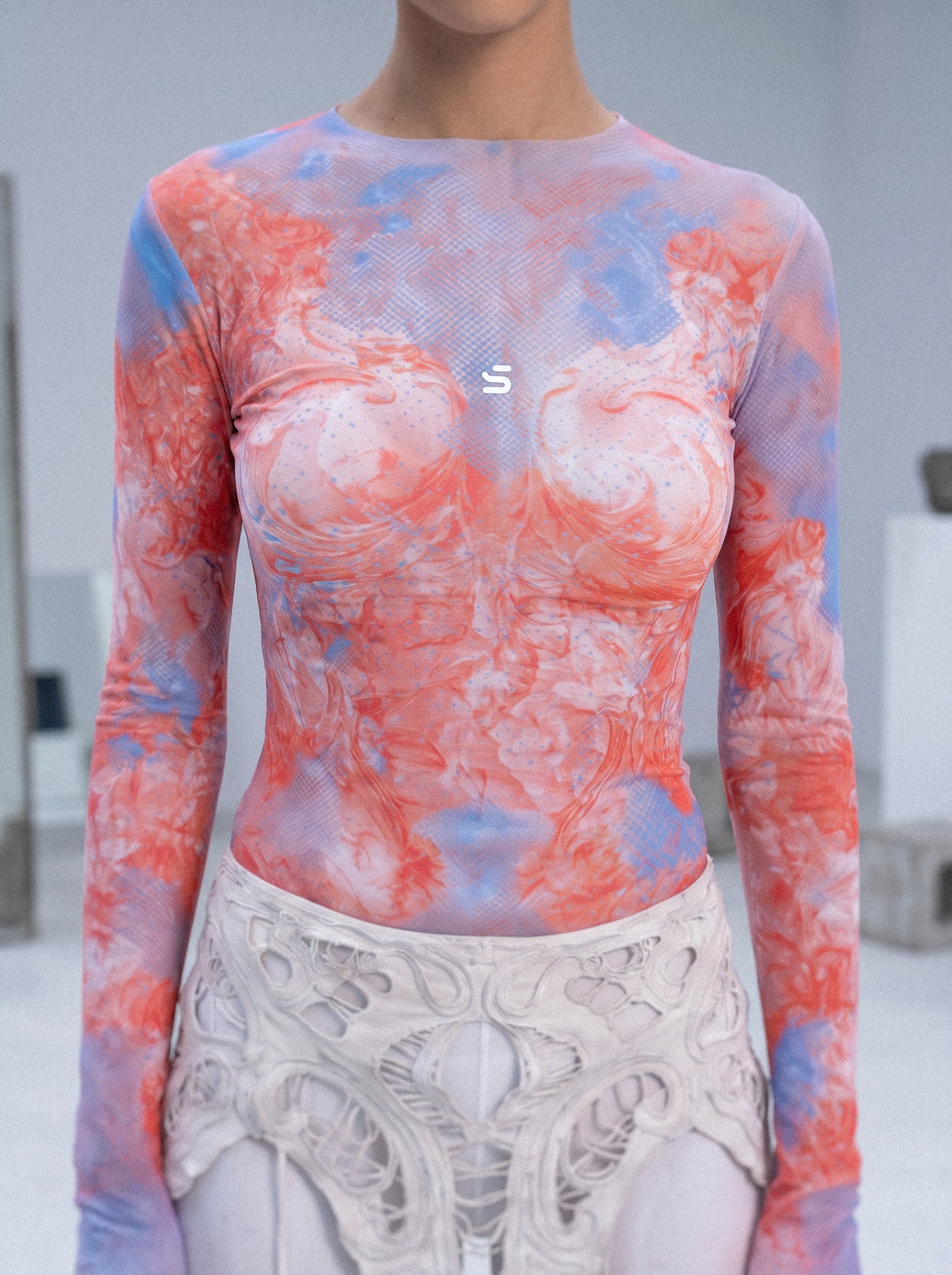 Person wearing a colorful long-sleeve top with a brand logo in an indoor setting